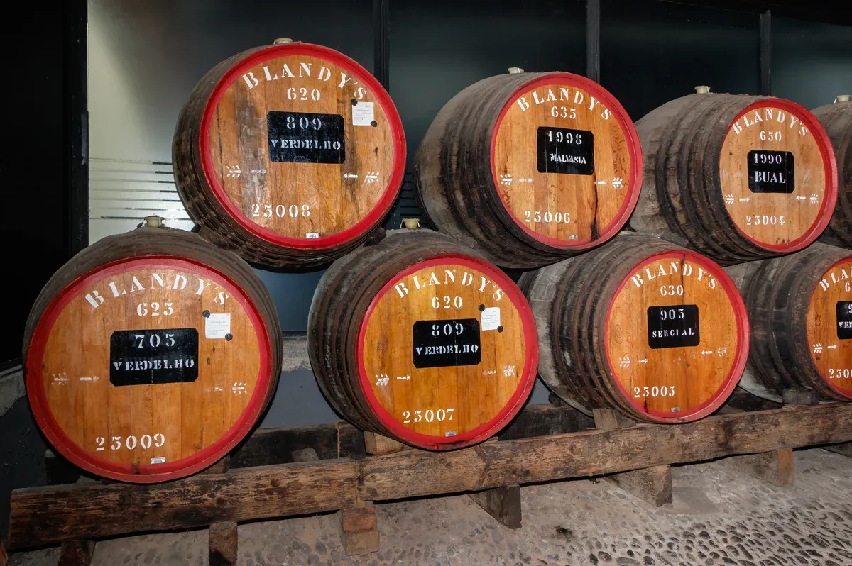 Wooden Blandy's wine barrels labelled Verdelho, Malvasia, Bual and Sercial stacked inside the wine lodge in Funchal, Madeira