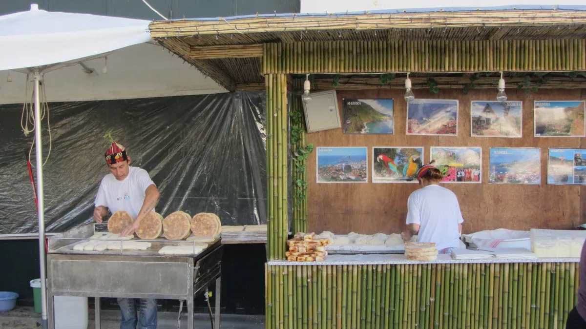 A street vendor making bolo do caco bread on a hot griddle at a stall in Funchal, Portugal