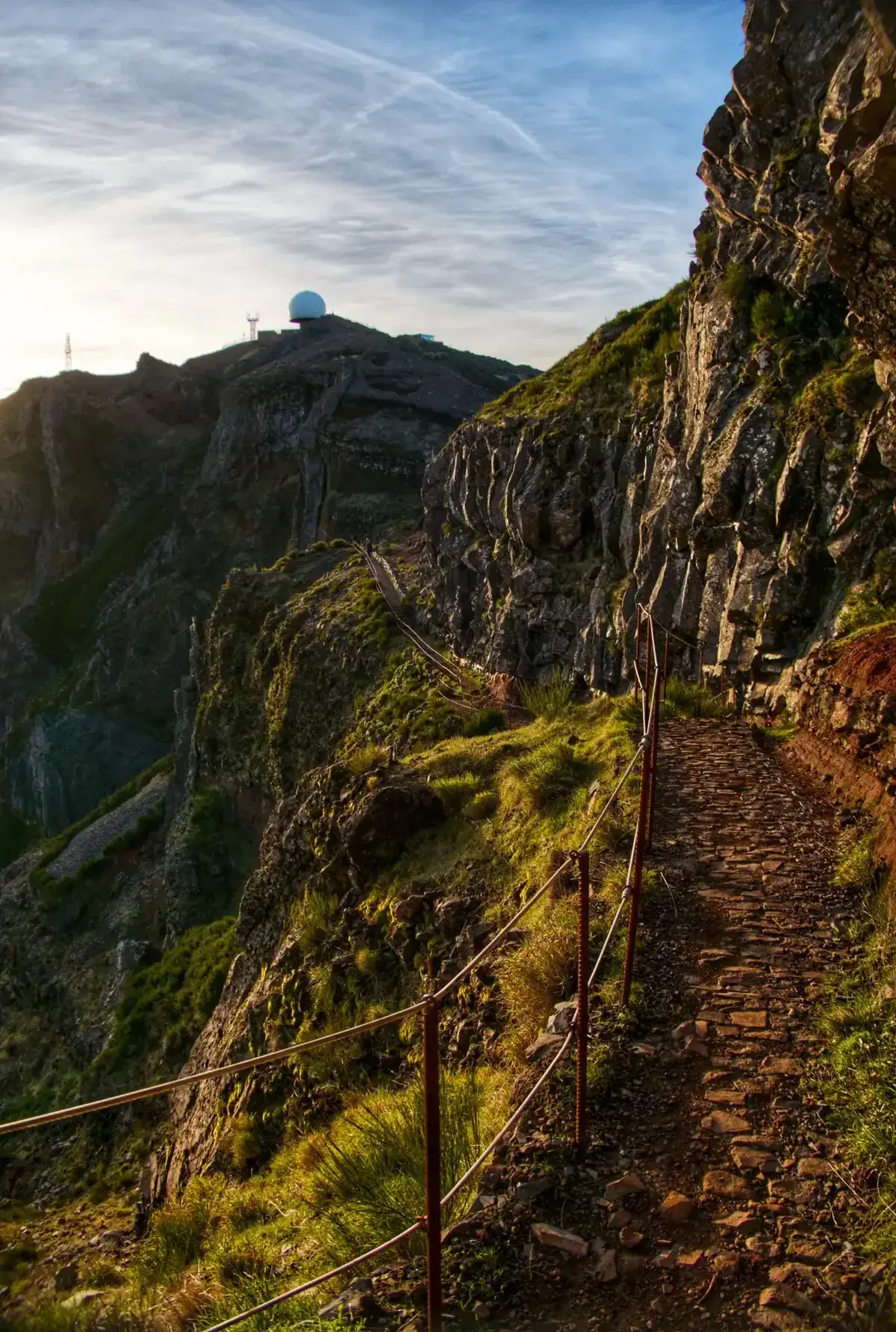 The PR1 trail with a rope handrail leading towards the radar dome at the summit of Pico do Arieiro near Funchal, Madeira