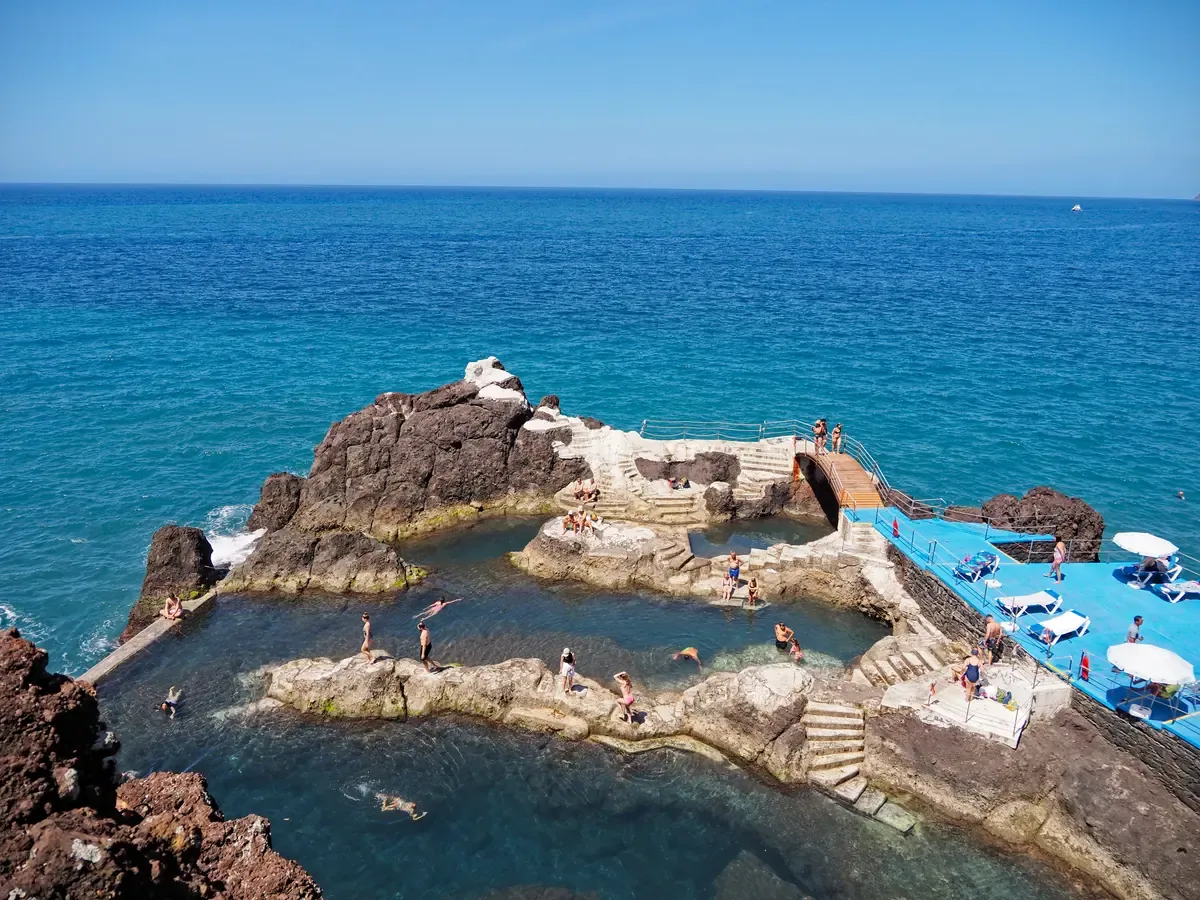 Swimmers in the natural rock pools of Doca do Cavacas bathing complex against the open Atlantic in Funchal, Madeira, Portugal