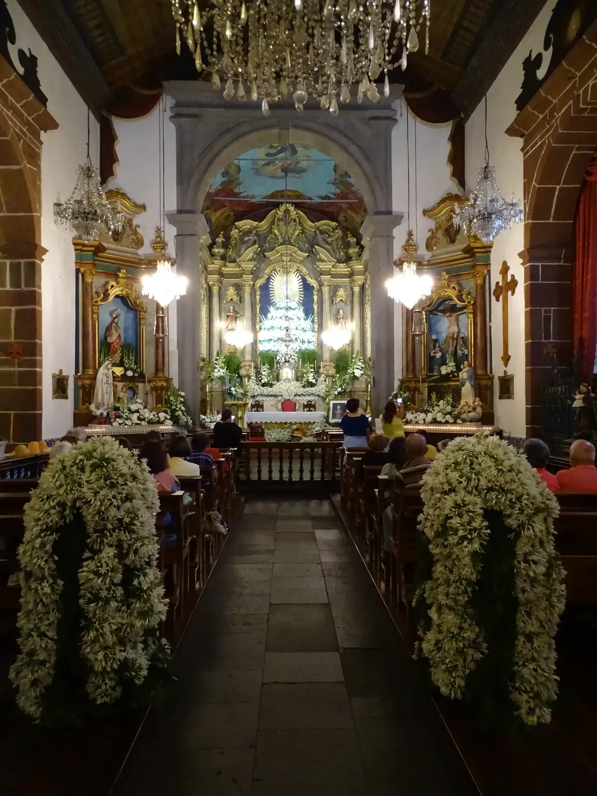 The flower-decked nave and altar inside Nossa Senhora do Monte church during the August feast, Funchal, Madeira