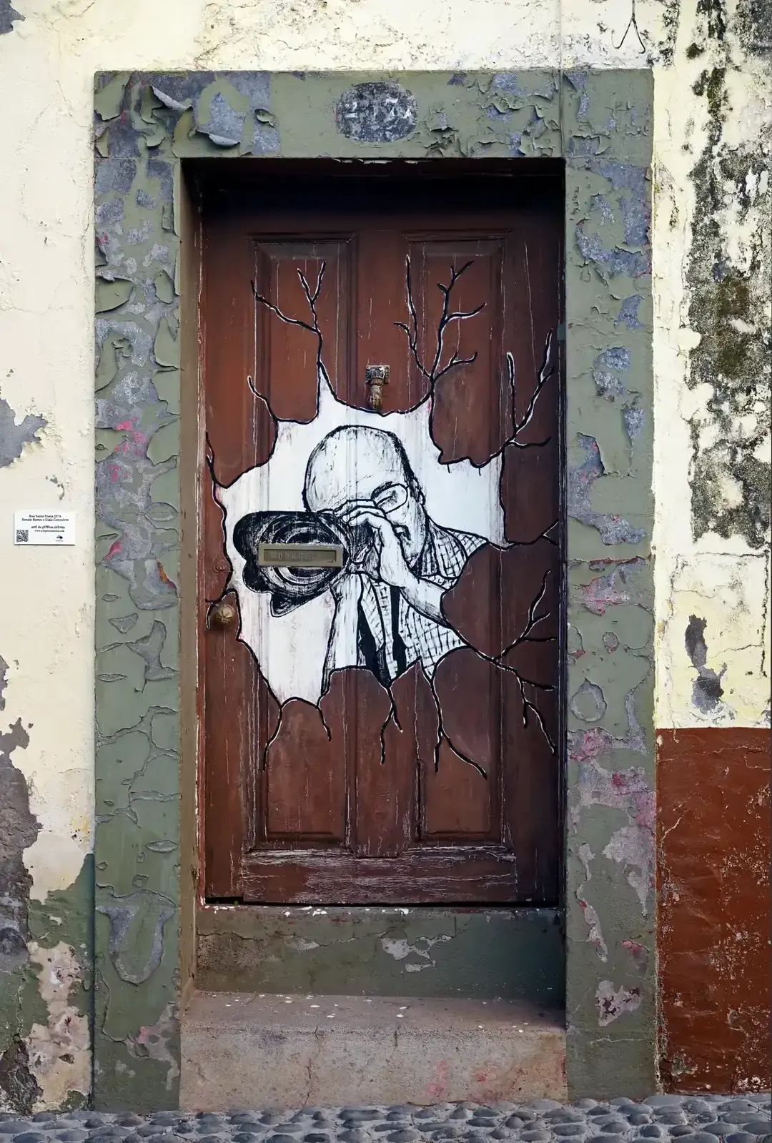 A painted door showing a photographer, part of the Art of Open Doors project on Rua de Santa Maria, Funchal, Madeira