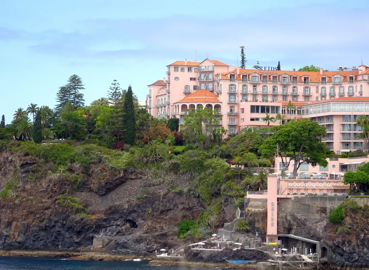 Reid's Palace hotel viewed from the sea, its pink facade above the cliffside Tea Terrace in Funchal, Madeira, Portugal